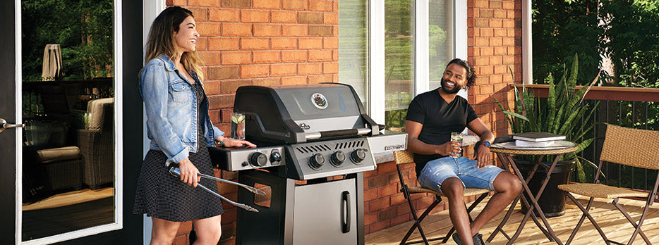 A couple outdoors on their patio enjoying grilling out in the summer with a Freestanding Grill and ice cold drinks in their hands